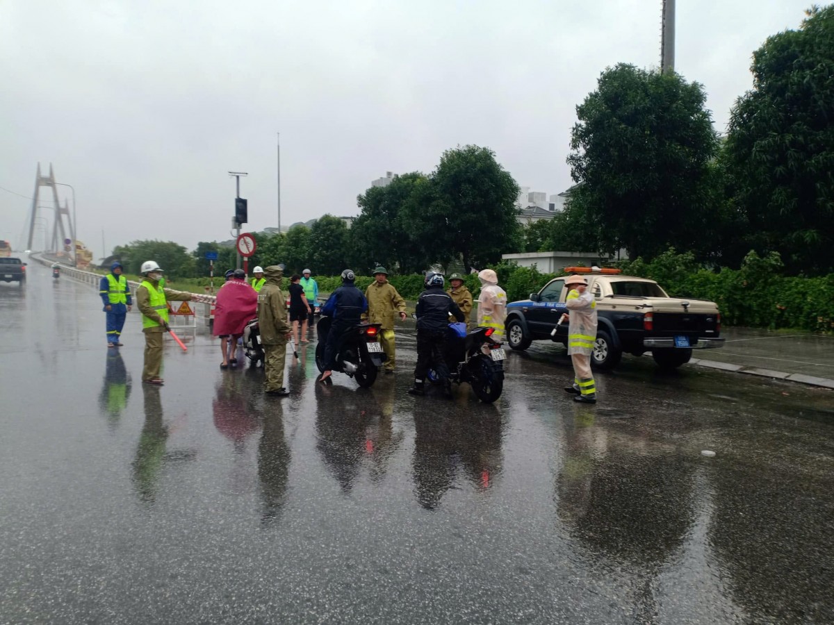 Lực lượng thanh tra giao thông và công an giao thông che gió bão cho người dân đi qua cầu