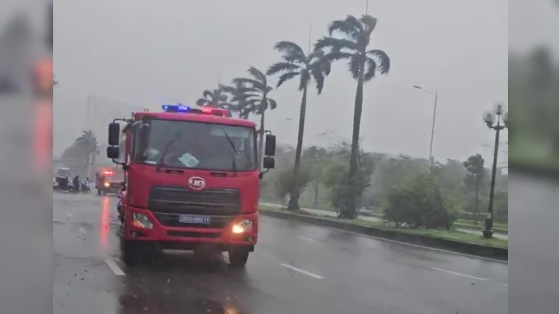 Xe chữa cháy che chắn cho hàng chục phương tiện đi qua cầu vượt trong cơn mưa bão ở Hà Nội