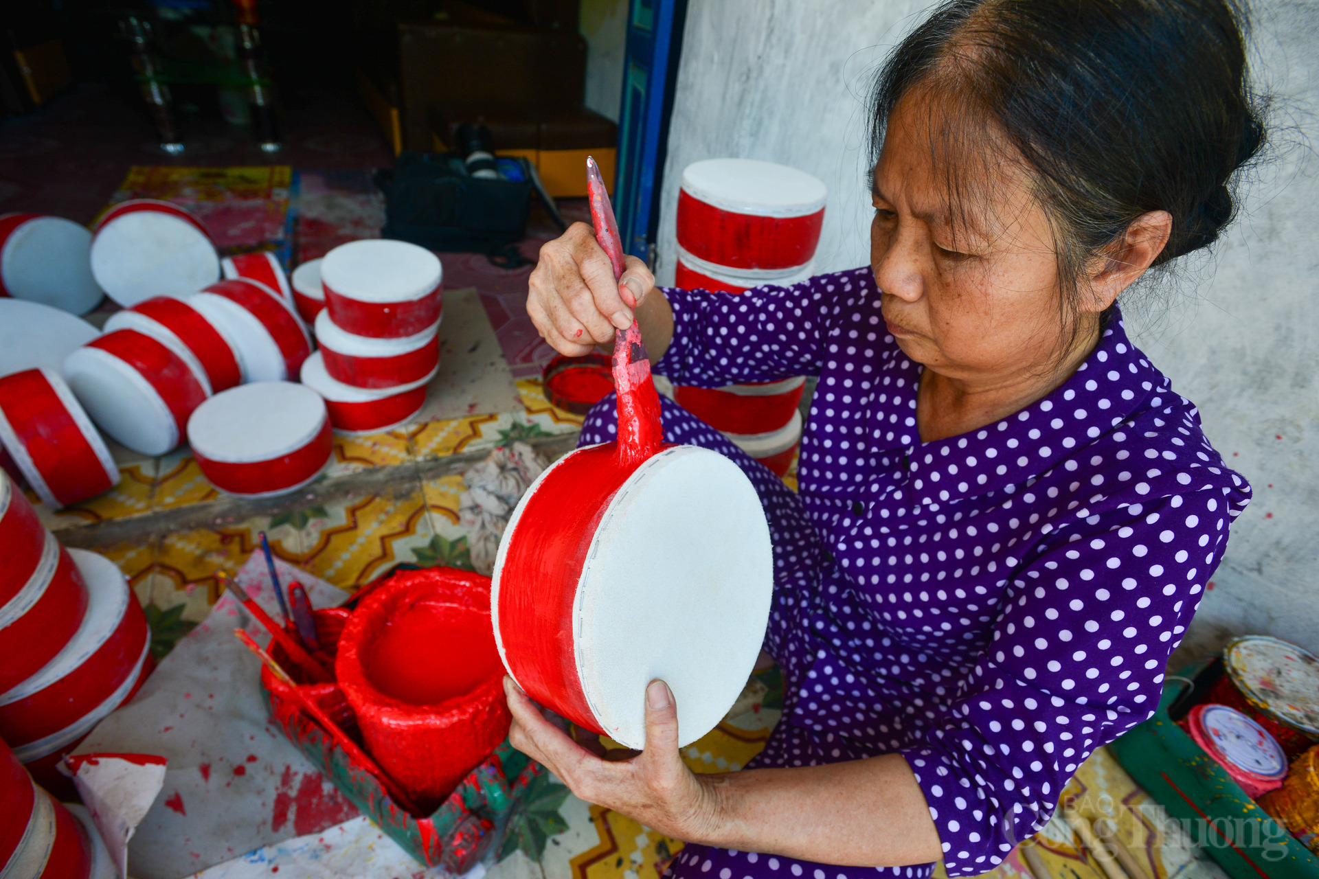 Để chiếc trống trở nên bắt mắt không thể bỏ qua công đoạn sơn màu. Khi công đoạn sơn màu hoàn tất cũng là lúc sản phẩm được đóng tai. Bà Là nói, trống phải làm từ da tốt thì trống mới kêu hay, da kém hay khung gỗ chưa phơi khô sẽ kém tiếng. Theo bà Là, trống Ông Hảo có tới 7 kích cỡ khác nhau dành cho lứa tuổi từ 5 tuổi cho đến 15 - 16 tuổi.