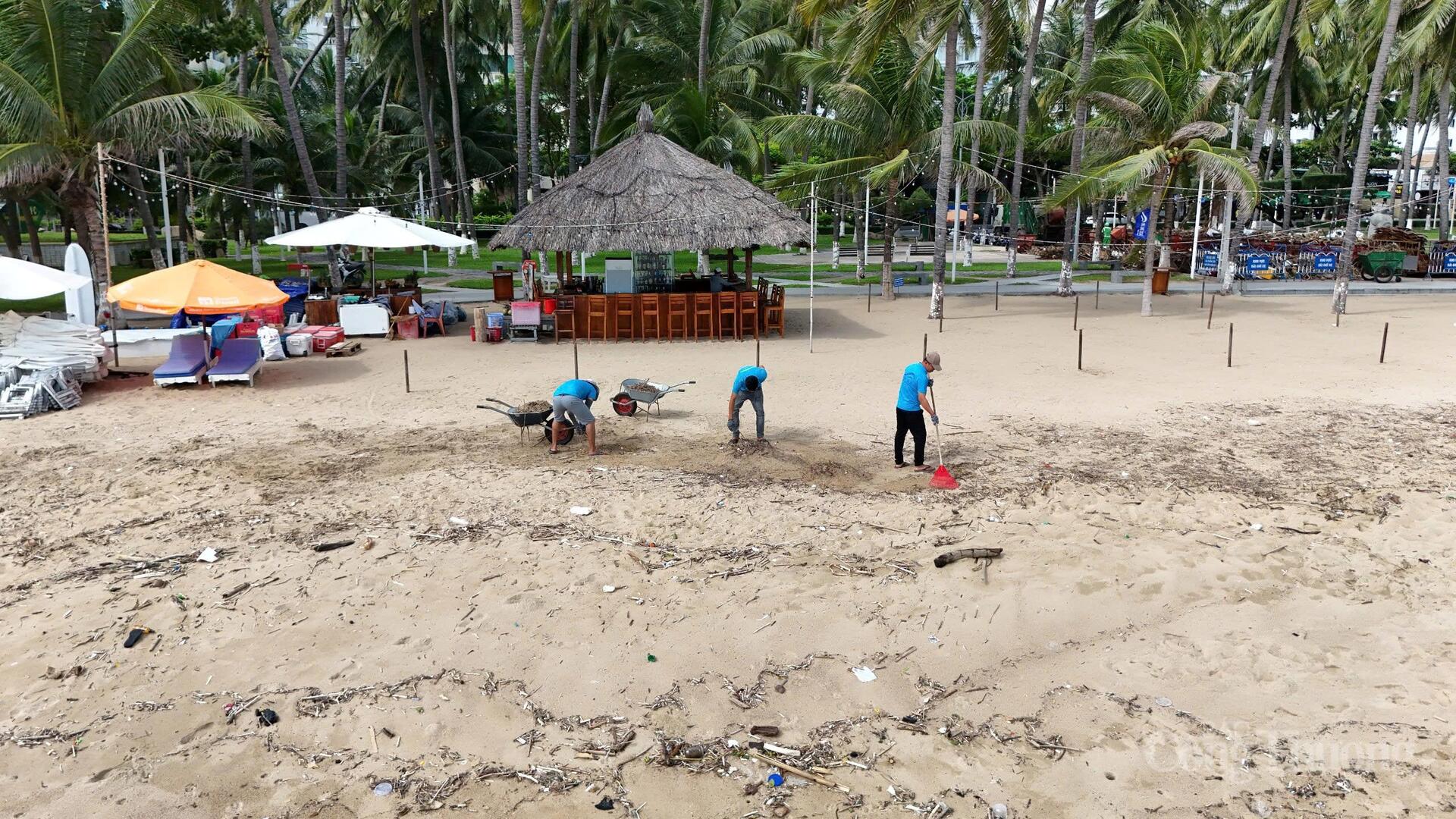 Người dân dùng cào tay để gom rác nhỏ lẫn trong cát do thủy triều đánh lên. Ảnh: Lê Sơn