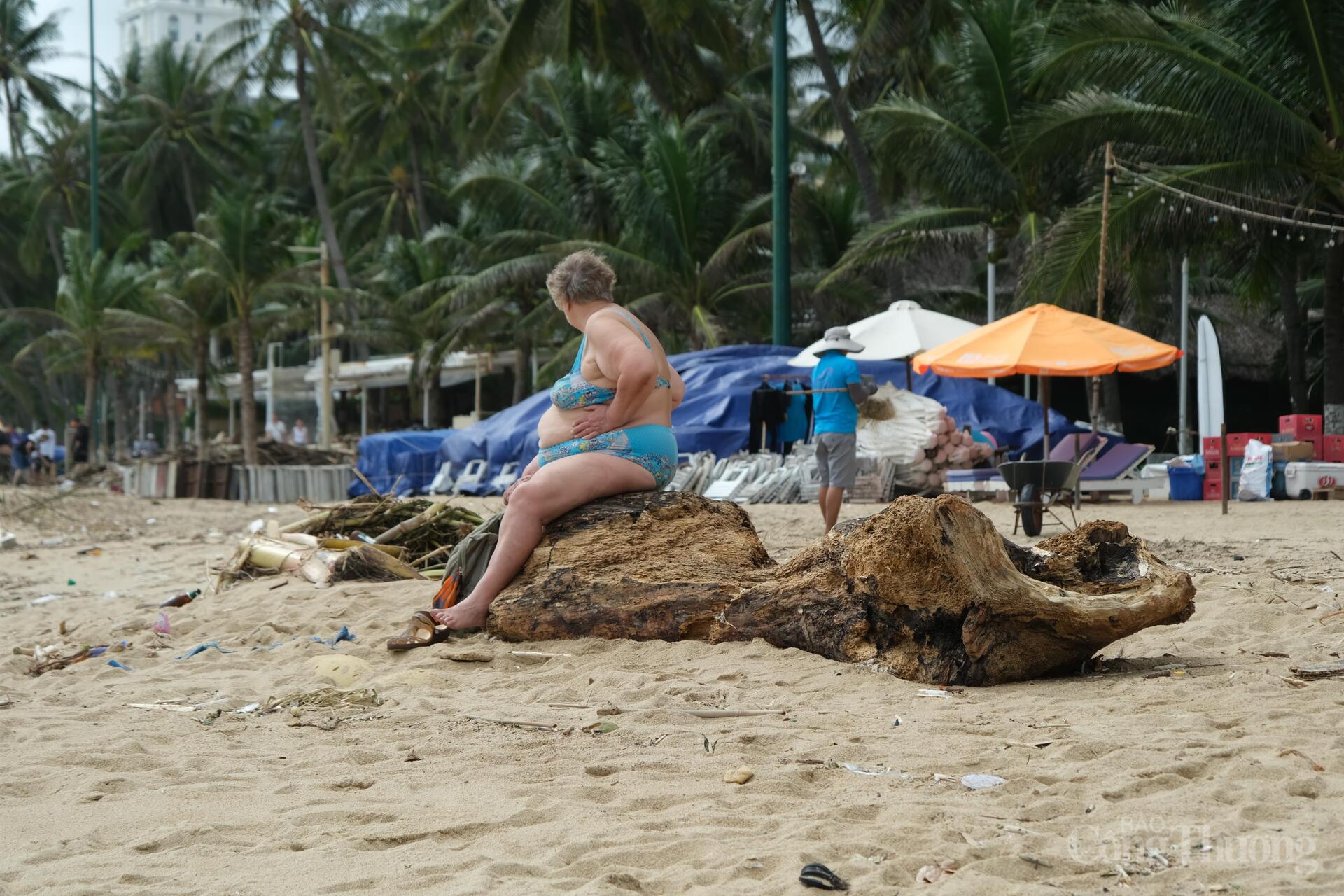 Du khách ngồi trên khúc gỗ nặng hàng trăm kí trôi dạt vào bờ biển. Ảnh: Lê Sơn