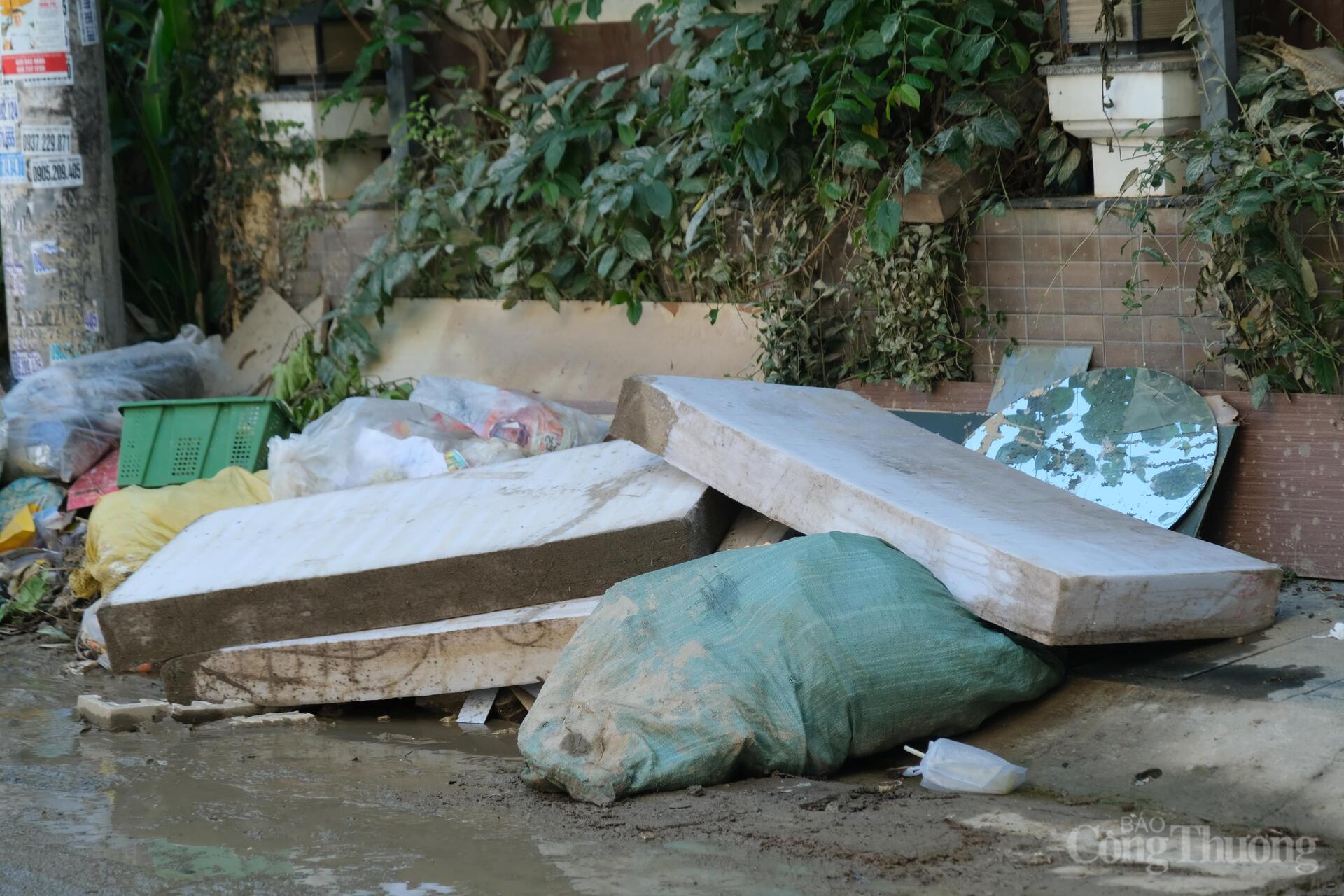 Đồ dùng sinh hoạt của người dân xen lẫn với rác thải trôi ra đường khi nước lũ rút. Ảnh: Lê Sơn