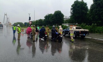 Lực lượng thanh tra giao thông và công an giao thông che gió bão cho người dân đi qua cầu