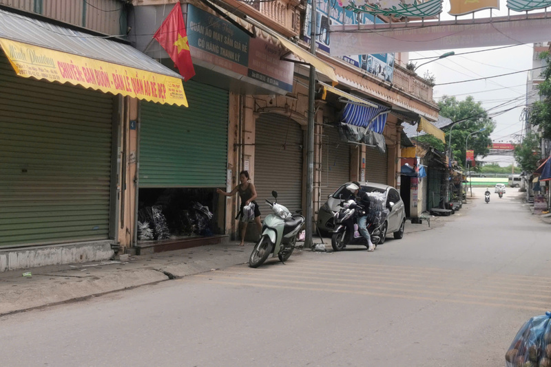 Một số cửa hàng hoạt động nhưng kéo cửa lưng chừng, việc xuất - nhập hàng hóa diễn ra vội vã sau đó liền đóng cửa ở bên trong. Ảnh: Bảo An
