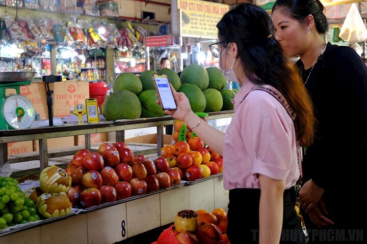 Tiểu thương hướng dẫn khách hàng thanh toán bằng hình thức quét mã QR. Ảnh: Hồng Hạnh