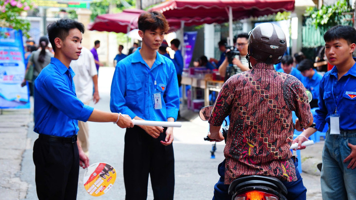 Tình nguyện viên hướng dẫn phương hướng cho phụ huynh thí sinh (Ảnh: Phương Ly)