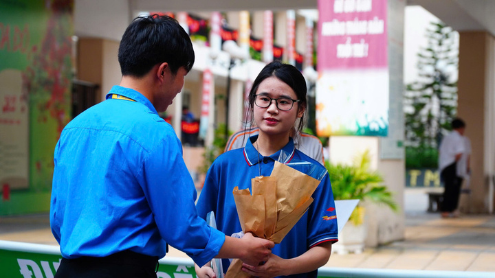 Tình nguyện viên tặng hoa chúc mừng thí sinh hoàn thành kỳ thi (Ảnh: Phương Ly)