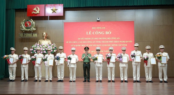 Thiếu tướng Trần Xuân Ánh (bên trái) cùng Giám đốc Công an 11 địa phương nhận quyết định và hoa chúc mừng của Bộ trưởng Lương Tam Quang. Ảnh: Bộ Công an