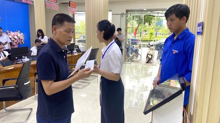 Đoàn thanh niên hỗ trợ người dân lấy số thực hiện thủ tục hành chính. Ảnh: Thu Anh