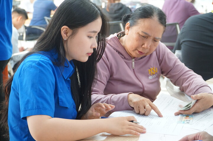 Đối với những người lớn tuổi hoặc không quen thao tác các thủ tục hành chính trực tuyến, sẽ có các bạn đoàn viên thanh niên trực tiếp hỗ trợ nhập thông tin giúp. Ảnh: Vũ Lê