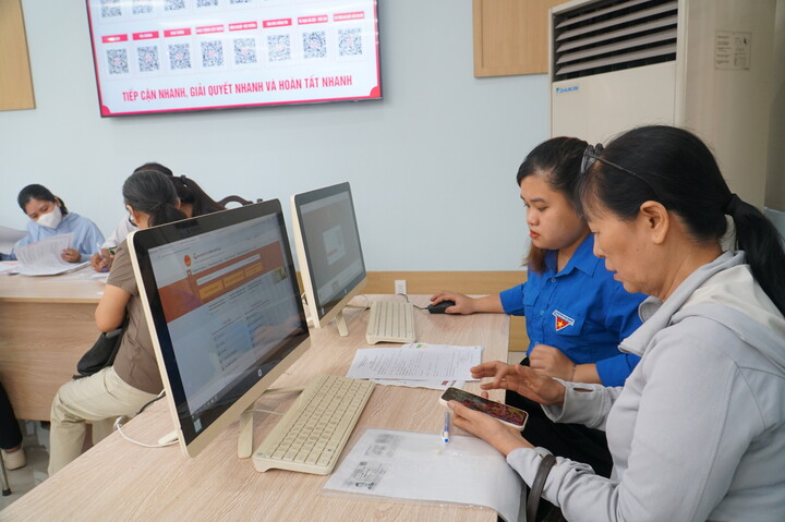 Một đoàn viên hỗ trợ bà Đặng Thị Hằng thực hiện thủ tục hành chính trực tuyến. Ảnh: Vũ Lê