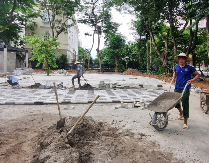 Đội thợ lát gạch tại một góc công viên dưới tiết trời oi nóng.