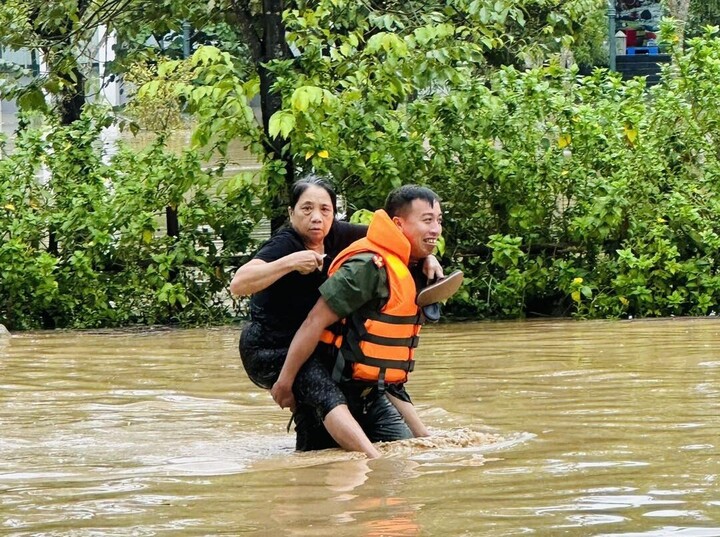 Cán bộ Công an tỉnh Nghệ An cõng người dân qua vùng ngập. Ảnh: Công an Nghệ An