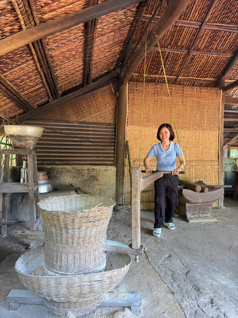 Du khách trải nghiệm cối xay lúa truyền thống của người dân trong Địa đạo Củ Chi