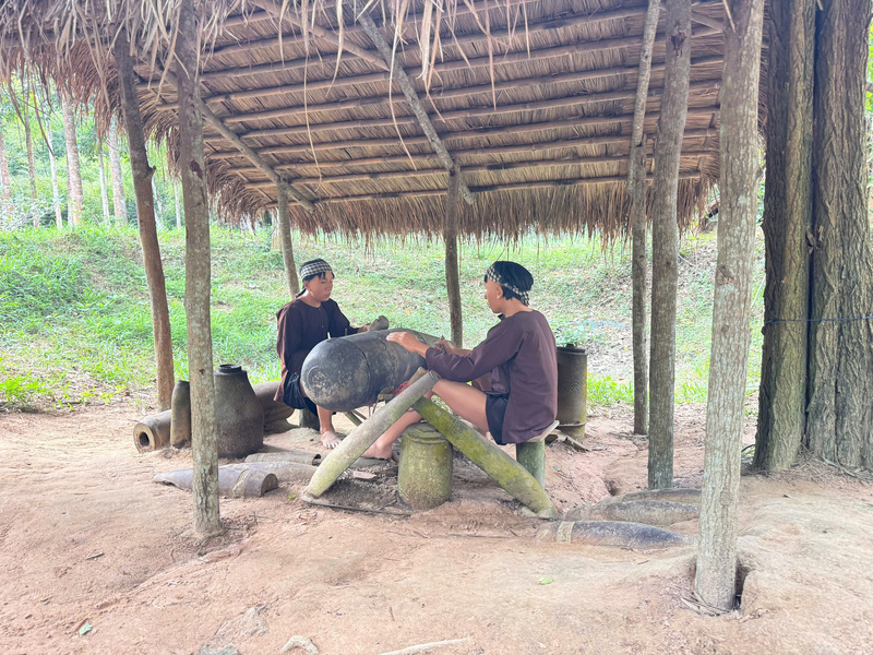 Bên trong mái lá đơn sơ, hai chiến sĩ du kích đang cưa quả bom chưa nổ, là “chiến lợi phẩm” của quân địch