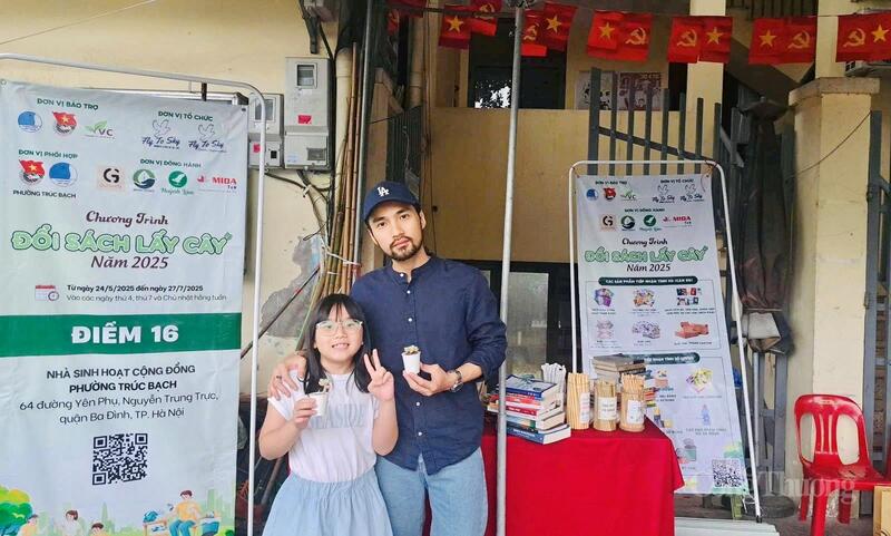 Hai bố con "check-in" sau khi nhận cây xanh tại Điểm đổi sách lấy cây số 16 tại TP. Hà Nội.