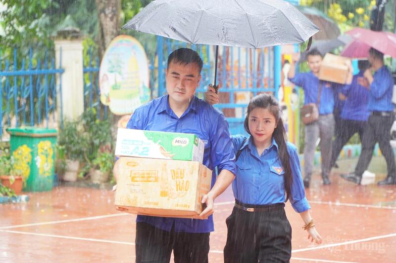 Các đoàn viên, thanh niên vận chuyển những phần quà dưới trời mưa nặng hạt.