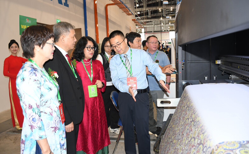 Doanh nghiệp giới thiệu kỹ thuật công nghệ in thêu, đặc biệt là in kỹ thuật số với đại biểu tại sự kiện. Ảnh: Minh Khuê.