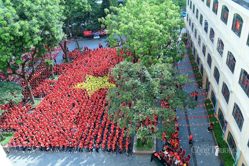Tại sân trường, các em học sinh mặc áo cờ đỏ sao vàng tạo không gian rực rỡ