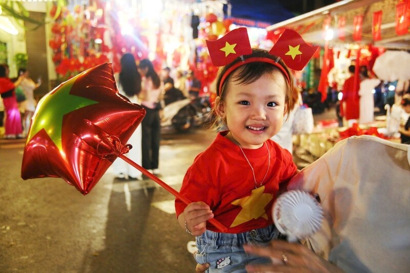 Nhiều em nhỏ được phụ huynh đưa tới các cửa hàng chọn mua áo đỏ, cờ Tổ quốc và chụp ảnh lưu niệm trong thời khắc thiêng liêng chuẩn bị Quốc khánh 2/9.