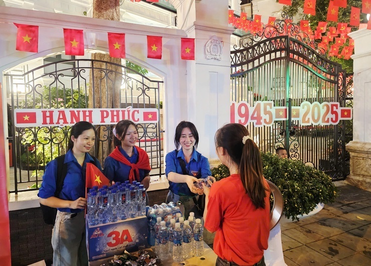 Người dân được các tình nguyện viên phát nước miến phí ngay cổng Trung tâm Báo chí Thủ đô. Ảnh: Linh Phạm