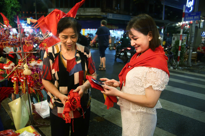 Cô Hà Thân (bên trái), tiểu thương phố Hàng Mã, hơn một tháng nay bán hàng từ sáng đến tối, liên tục nhập cờ và áo đỏ sao vàng để phục vụ người mua dịp Quốc khánh 2/9.