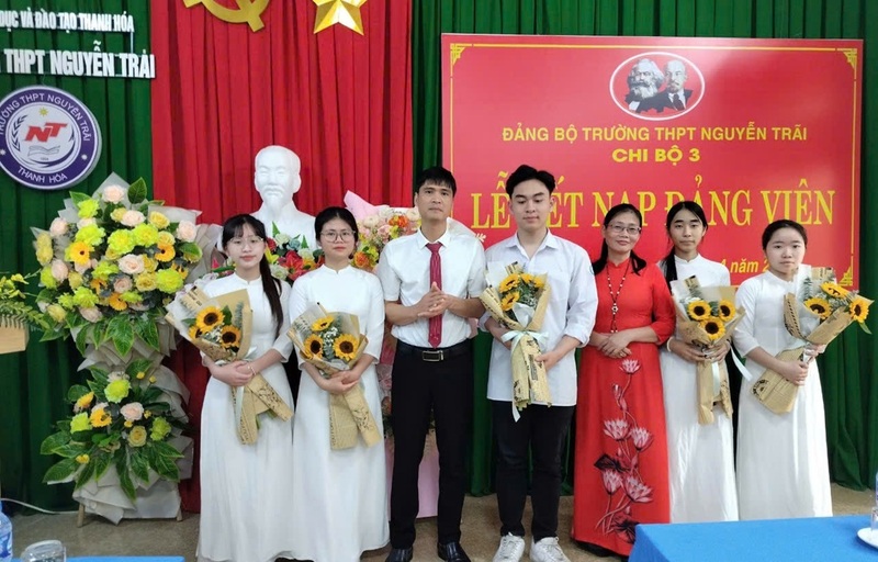 Thầy giáo Nguyễn Anh Thế, Hiệu trưởng Trường THPT Nguyễn Trãi tặng hoa chúc mừng các em học sinh ưu tú được kết nạp vào Đảng. Ảnh: Nguyễn Thế