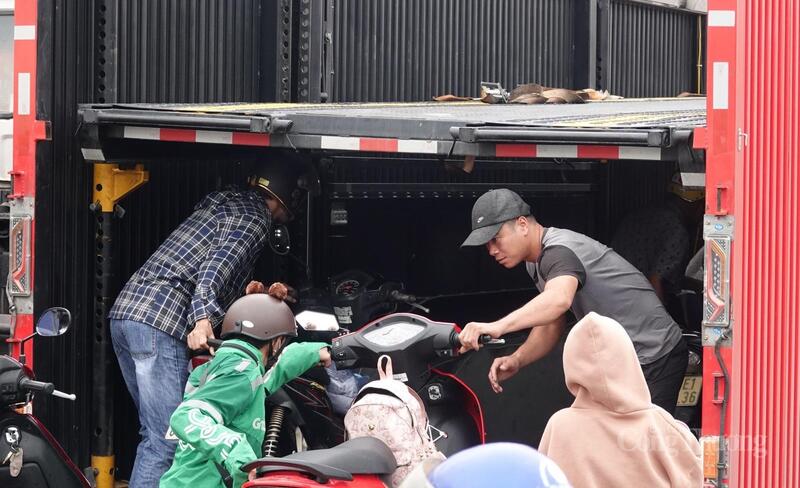 Các phương tiện lần lượt di chuyển lên xe tải. Một chủ phương tiện chia sẻ: Rất may có lực lượng cảnh sát giao thông đề nghị xe tải cho đi nhờ, chứ không thì không biết khi nào mới qua được"