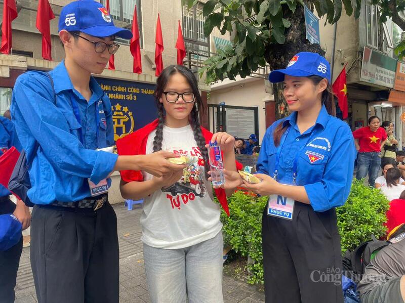 Thu Hà (bên phải) cùng trao những chai nước và bánh cho người dân xem sơ duyệt diễu binh