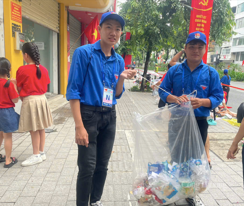Hồng Sơn (tay trái) thu gom rác thải trên đường Kim Mã chiều 27/8