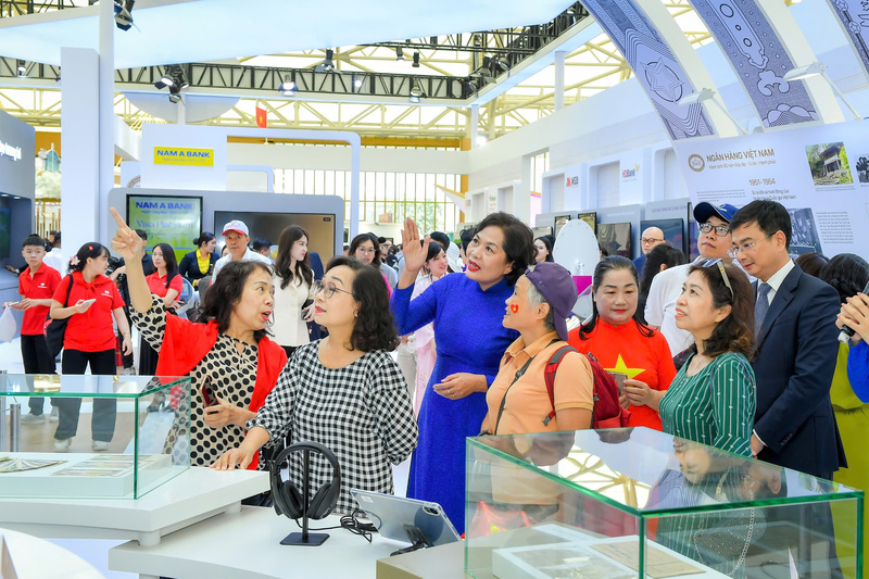 Lãnh đạo Ngân hàng Nhà nước trực tiếp giới thiệu với khách tham quan triển lãm những thành tựu của ngành Ngân hàng. Ảnh: SBV