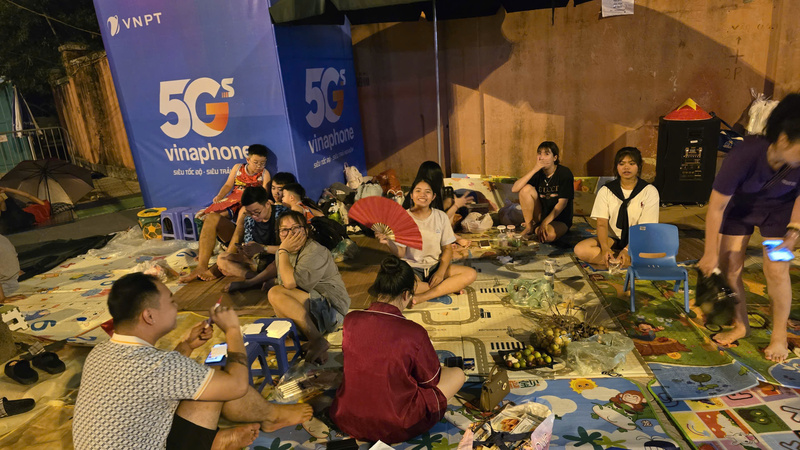 Trên vỉa hè trung tâm Hà Nội, nhiều nhóm bạn trẻ trải chiếu, dựng ghế, chuẩn bị đồ ăn thức uống để chờ xem diễu binh mừng Quốc khánh