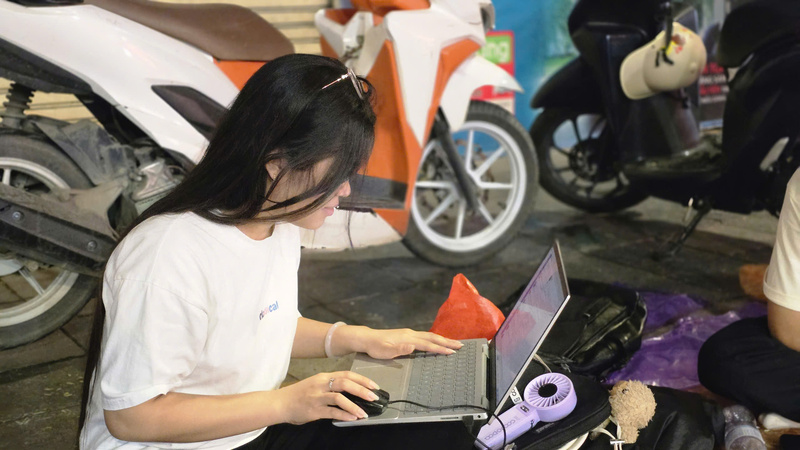 Một bạn trẻ tranh thủ mở laptop làm việc ngay trên vỉa hè