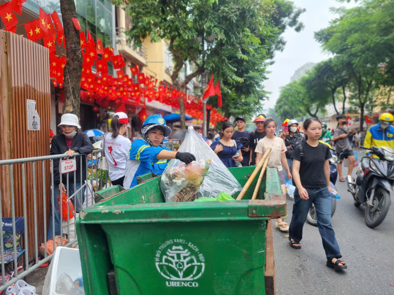Trên đường Nguyễn Thái Học, giữa dòng người đông đúc chờ xem sự kiện A80, công nhân môi trường vẫn miệt mài thu gom rác, giữ phố phường sạch đẹp, rực rỡ cờ hoa.