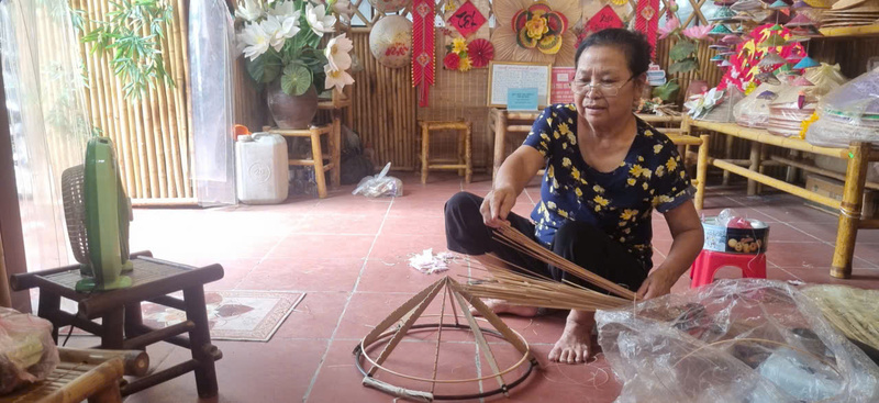 Cô Chính thực hiện công đoạn làm vòng khung nón tại gian trưng bày của nghệ nhân Tạ Thu Hương ở Trung tâm OCOP làng Chuông.