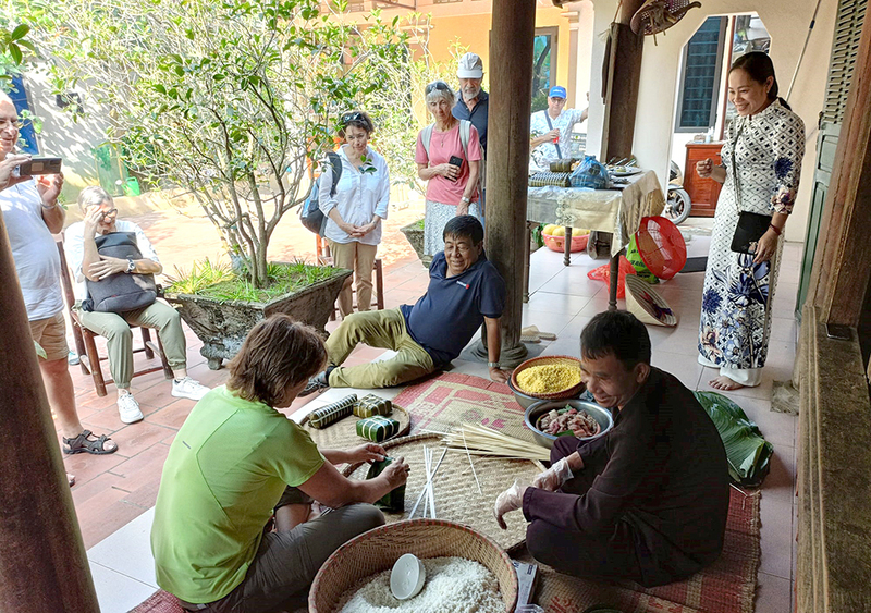 Du khách nước ngoài trải nghiệm gói bánh chưng tại điểm du lịch cộng đồng Hùng Lô, xã Hùng Lô (nay là phường Vân Phú, tỉnh Phú Thọ). Ảnh: Quân Lâm