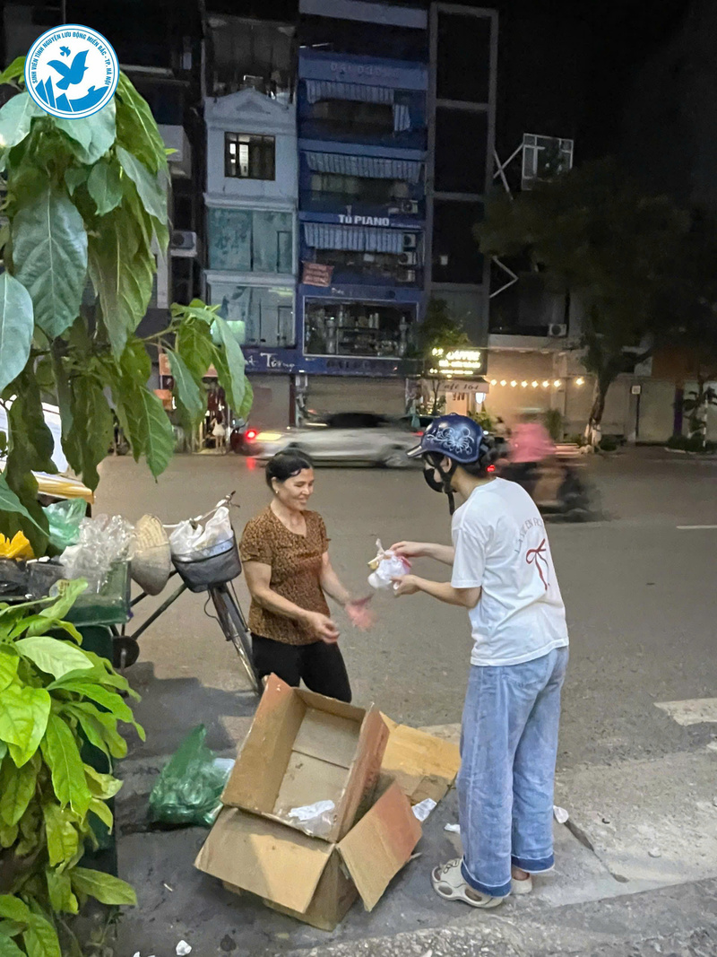 Một phụ nữ nhặt ve chai nhận phần cơm từ sinh viên tình nguyện trong hành trình '‘Đêm ấm’'. Ảnh Bùi Thành