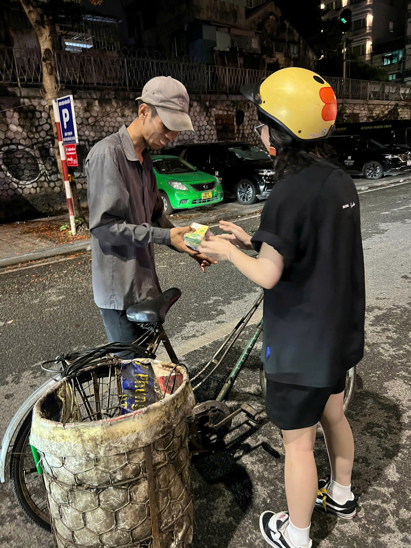Tình nguyện viên trao tận tay phần quà đêm muộn cho một người lao động lúc 1 giờ sáng trên phố Phùng Hưng ở Hà Nội. Ảnh: Bùi Thành