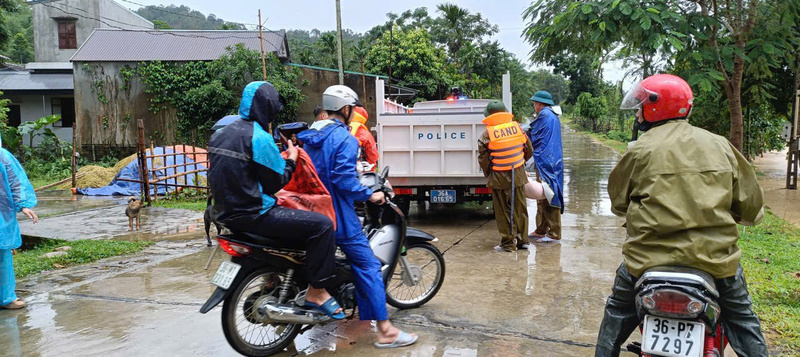 Cán bộ Công an xã Xuân Chinh hỗ trợ người dân di chuyển tài sản khỏi vùng nguy hiểm. Ảnh: Công an Thanh Hóa