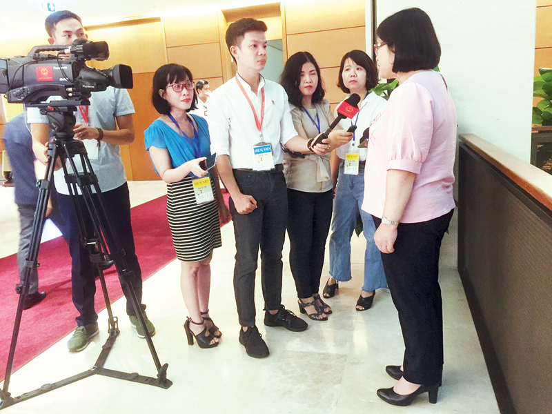 Phóng viên Báo Công Thương (thứ hai từ trái sang) phỏng vấn đại biểu bên hành lang Quốc hội