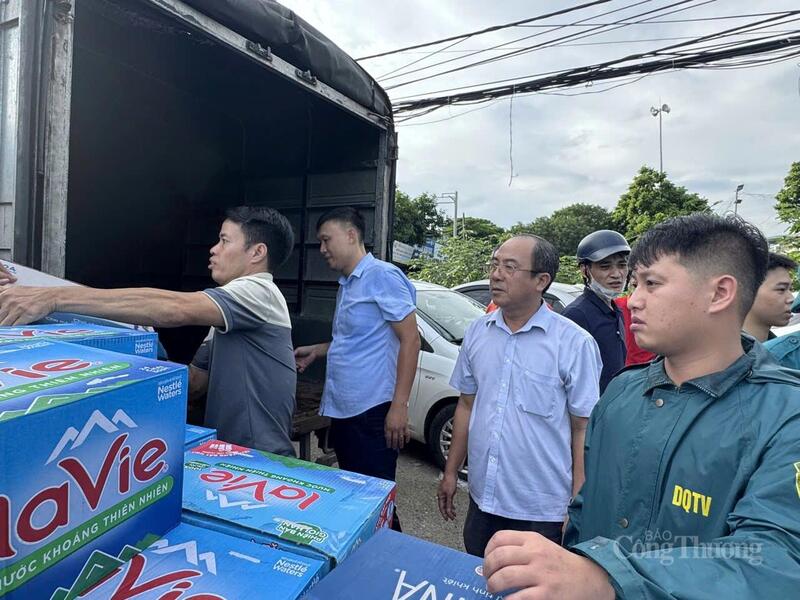 Ông Phạm Hải Hoạt (đeo kính, ở giữa), chủ tịch Ủy ban MTTQ phường Từ Liêm trực tiếp tham gia cấp phát nhu yếu phẩm cho các hộ dân bị ngập.
