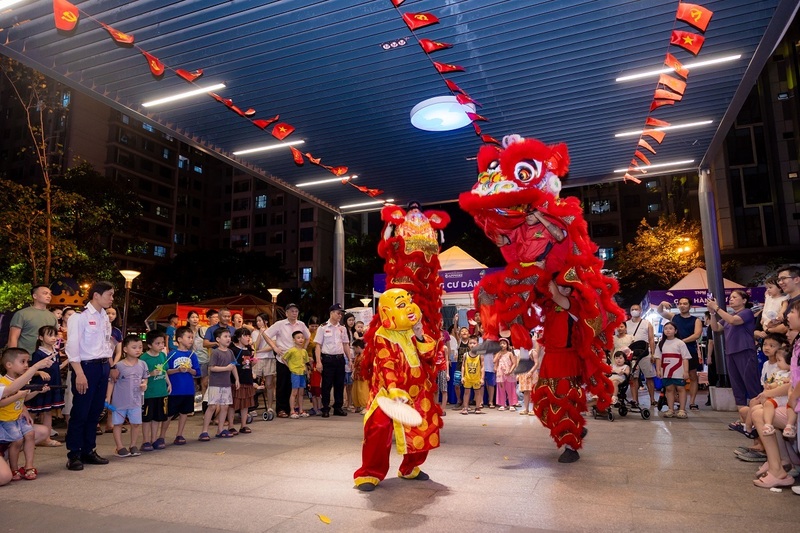 Đoàn diễu hành lân sư rồng với tiếng trống rộn rã, mang không khí Trung thu lan tỏa khắp khu đô thị. Những em nhỏ háo hức chạy theo đoàn lân, đôi mắt rạng rỡ niềm vui.