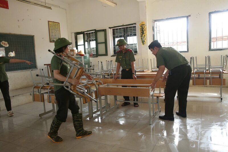Chuyển bàn ghế được rửa sạch bùn đất vào trong lớp học.