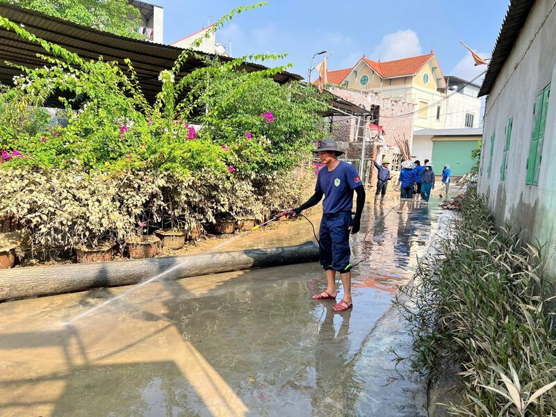 Vệ sinh, rửa sạch bùn đất trên đường làng.