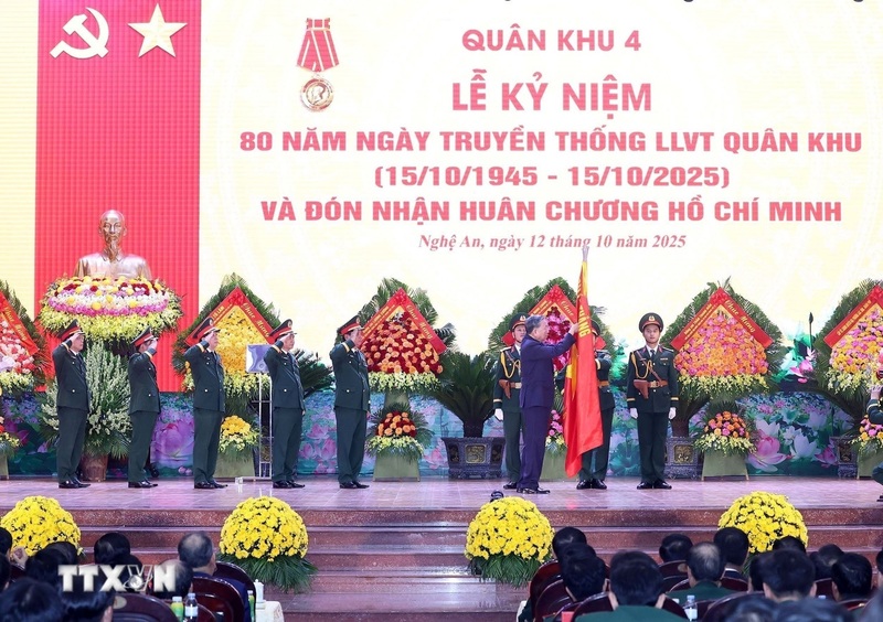 Tổng Bí thư Tô Lâm gắn Huân chương Hồ Chí Minh lên lá cờ truyền thống của Quân khu 4. Ảnh: Thống Nhất/TTXVN