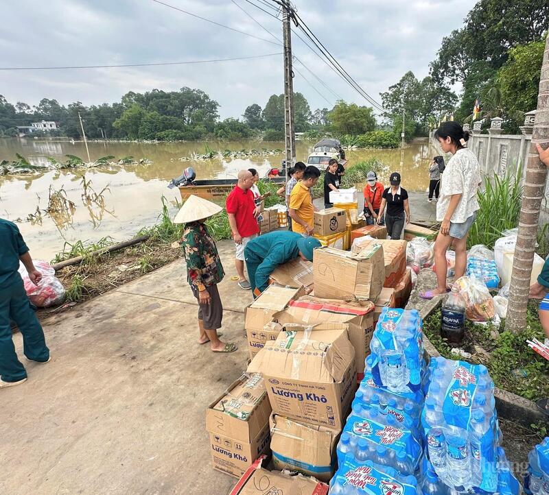Đoàn thiện nguyện trao quà hỗ trợ gồm nước uống, mì tôm và nhu yếu phẩm thiết yếu cho các hộ dân bị cô lập do ngập lụt. Ảnh: TNTB