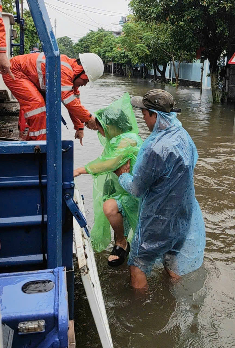 Nước dâng cao, công nhân ngành điện thành phố Huế dùng xe chuyên dụng chở người dân vùng lũ đến nơi an toàn. Ảnh: Nguyễn Tuấn