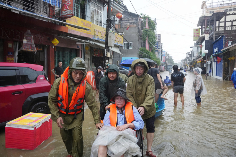 Ông Phan Thiên Định - Chủ tịch UBND thành phố Huế (bên phải) trực tiếp đẩy bệnh nhân trên xe lăn di chuyển ra khỏi vùng lũ. Ảnh: Nguyễn Tuấn