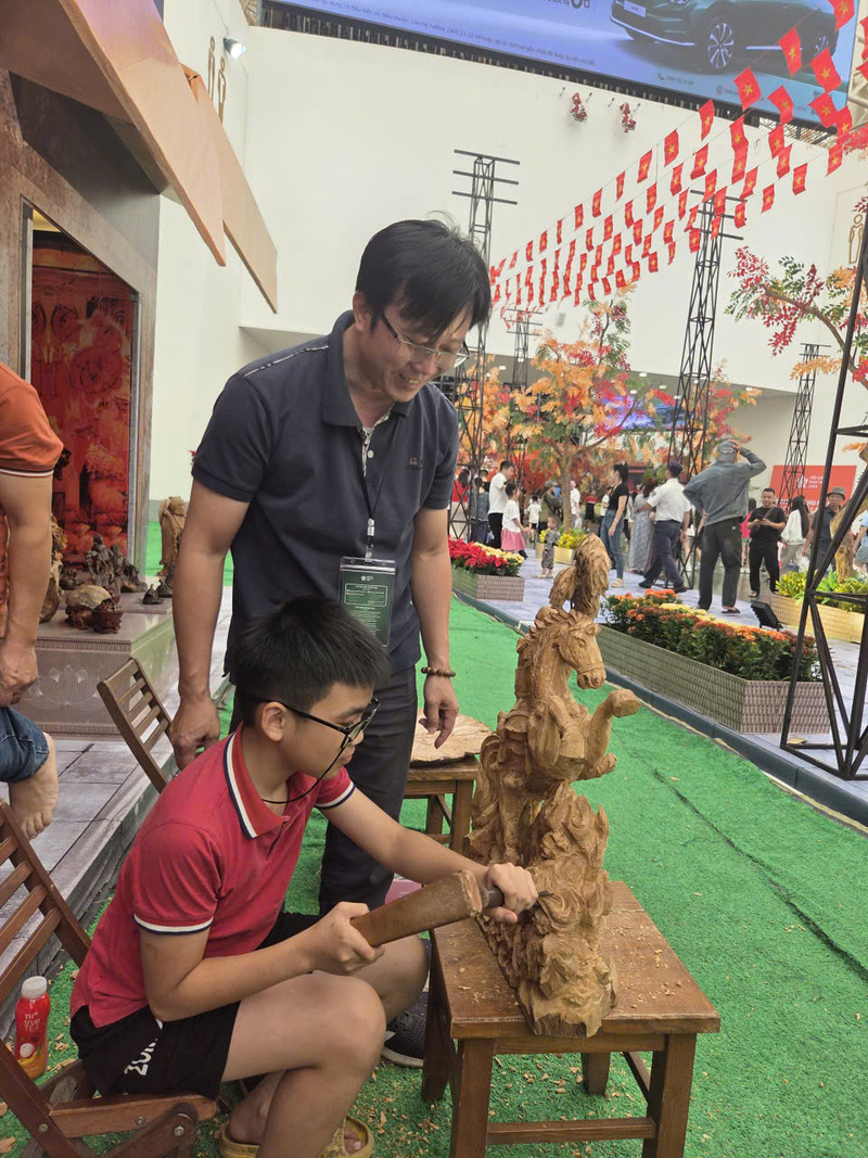 Nghệ nhân ưu tú Đỗ Văn Cường hướng dẫn các em nhỏ trải nghiệm đục gỗ. Ảnh: Hoài Thanh.
