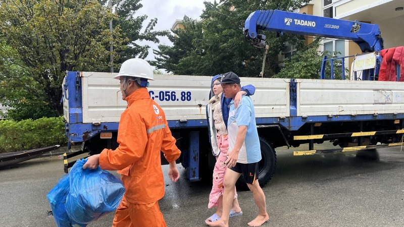 Nhân viên điện lực Huế hỗ trợ đưa nữ bệnh nhân đến bệnh viện Trung ương Huế. Ảnh: Bình An